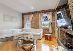 Una sala de estar moderna con un sofá blanco, un sillón de cuero, una mesa de centro y una chimenea.