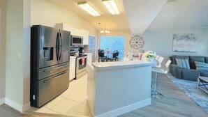 A modern kitchen with a large island, a dining area with a table and chairs, and a living room with a sofa and a coffee table. - Magical Villa by Disney  (Kissimmee)