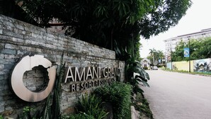 A stone wall with a sign for 'AMANI GRAND RESORT RESIDENCES.' - Experience affordable luxury in our cozy & homey staycation layover pad.  (Lapu-Lapu City)