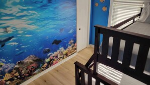 Une pièce avec un mur bleu et une fresque représentant une scène sous-marine.