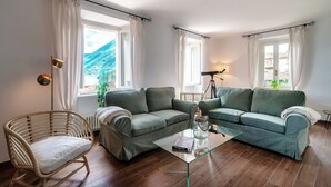 Ein Wohnzimmer mit einer Couch, einem Sessel, einem Glastisch und einer Lampe.