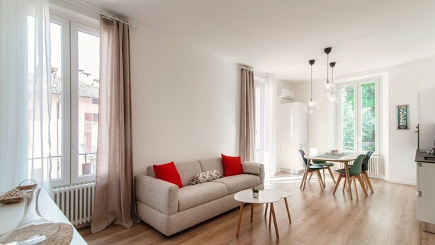 A modern living room with a sofa, dining table, chairs, and a coffee machine. - Dolce - MyHomeinComo (Como)