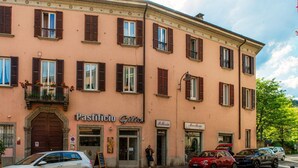 A building with a storefront labeled 'Pastificio Giltor' and another with 'Pellegrino.' There are parked cars in front. - Dolce - MyHomeinComo (Como)