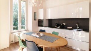 A modern kitchen with white cabinets, a black countertop, and a dining table with chairs. - Dolce - MyHomeinComo (Como)