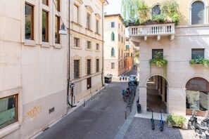 A narrow street with buildings on either side, a bicycle rack, and a few pedestrians.