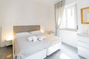 A hotel room with a bed, bedside table, and a window with curtains. - Corte Melone Residence 2 (Verona)