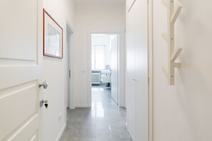 A hallway with white doors, a framed picture, and a view into a room with a radiator.