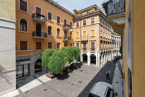 A courtyard with a tree, a car, and buildings with balconies.