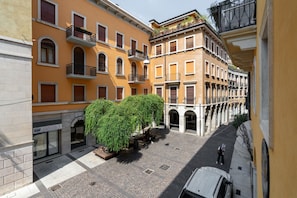 A courtyard with a tree, a car, and buildings with balconies. - Melon Court Residence 3 (Verona)