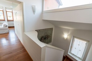 A modern interior with a curved white wall, a window with a white curtain, and a wooden floor. - Ponte Pietra Residence (Verona)