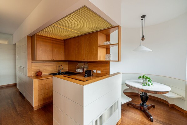 A modern kitchen with wooden cabinets, a built-in sink, and a round dining table with a white top. - Ponte Pietra Residence (Verona)