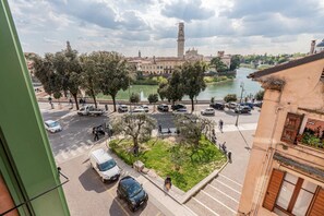 A view of a city square with a river, trees, and buildings in the background. - Ponte Pietra Residence (Verona)