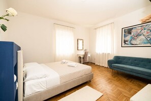 A bedroom with a bed, a desk, a chair, a sofa, and a painting on the wall. - Serego Residence - Elegant residence overlooking Porta Leoni (Verona)