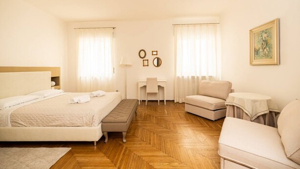 A hotel room with a large bed, a desk, a chair, and a sofa. - Serego Residence - Elegant residence overlooking Porta Leoni (Verona)