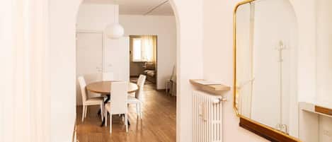 A modern interior with a dining area, a large mirror, and a radiator.