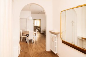 A modern interior with a dining area, a large mirror, and a radiator.