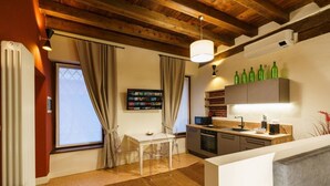 Une cuisine moderne avec un coin repas, des poutres apparentes en bois au plafond et un téléviseur fixé au mur.