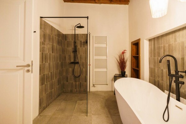 Une salle de bain moderne avec une douche à parois de verre, une baignoire sur pieds et une étagère en bois.