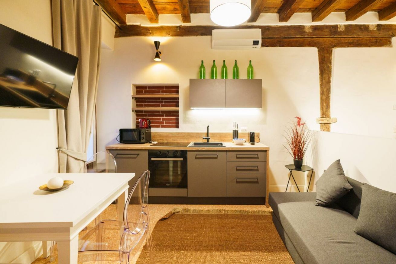 Una cucina compatta con angolo ristoro, divano e televisore.