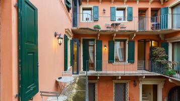 Un edificio a più piani con balconi, un tavolino e sedie all'esterno.