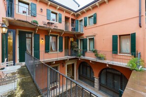 A multi-story building with balconies, a courtyard, and a small outdoor seating area. - Spacious and elegant Satyr residence with terrace (Verona)