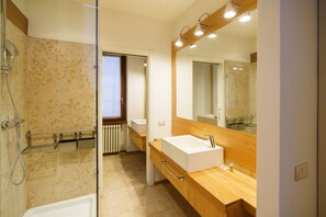 A modern bathroom with a glass shower enclosure, a wooden vanity with a white sink, and a large mirror above the sink. - Spacious and elegant Satyr residence with terrace (Verona)