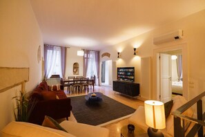 A living room with a sofa, coffee table, and TV stand. There is a dining area with a table and chairs. - Spacious and elegant Satyr residence with terrace (Verona)
