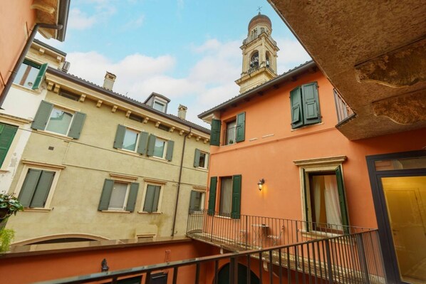 A courtyard with buildings featuring balconies and a bell tower. - Spacious and elegant Satyr residence with terrace (Verona)