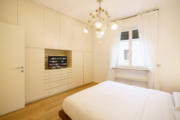 A bedroom with a bed, a wardrobe, a built-in TV shelf, and a window with curtains. - Luxurious Stella residence with balcony overlooking Arena (Verona)