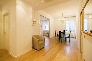 A room with a wooden floor, a dining table with chairs, a chandelier, and a door. - Luxurious Stella residence with balcony overlooking Arena (Verona)