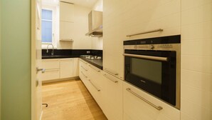 Eine Küche mit weißen Schränken, einer schwarzen Arbeitsplatte, einer Edelstahl-Dunstabzugshaube und einem Samsung-Backofen.