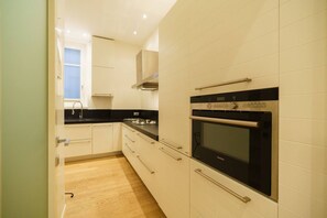 A kitchen with white cabinets, a black countertop, a stainless steel range hood, and a Samsung oven. - Luxurious Stella residence with balcony overlooking Arena (Verona)