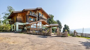 A multi-story wooden building with balconies, a stone entrance, and a gravel driveway. - Apartment 'Piccole Dolomiti' with Mountain View, Shared Terrace and Wi-Fi (Brentonico)