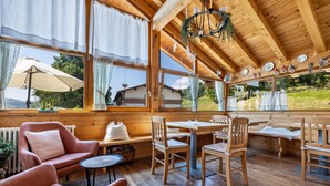A wooden interior with a dining area, seating, and large windows. - Apartment 'Piccole Dolomiti' with Mountain View, Shared Terrace and Wi-Fi (Brentonico)