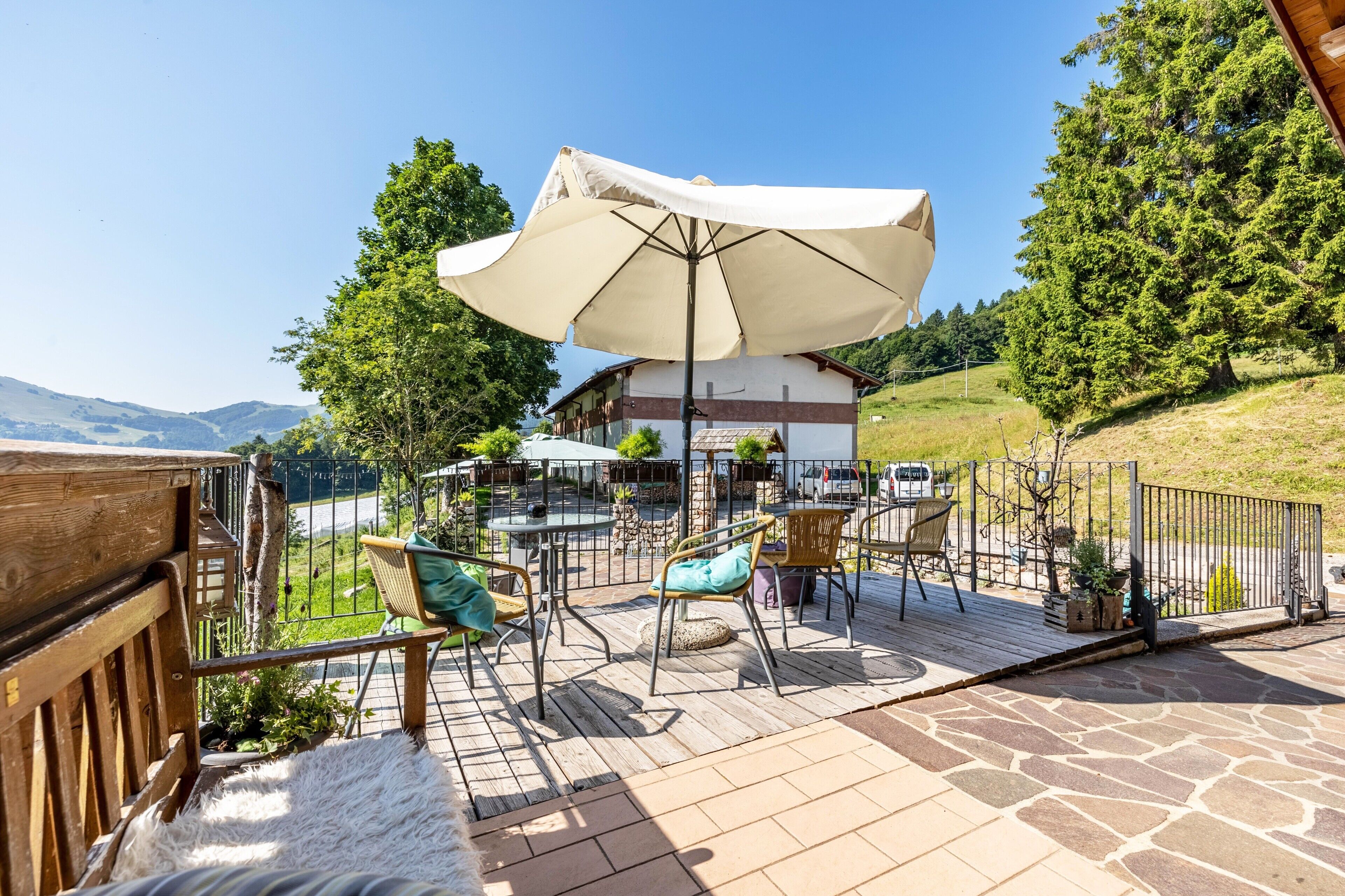 Een terras met buitenmeubels, een tafel en een grote parasol.