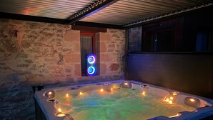 Een hottub met een achtergrond van een stenen muur, een raam met blauw licht, en een plafond met metalen rooster.
