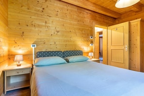 Una habitación con paneles de madera, una cama, mesitas de noche y una puerta.