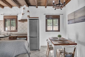 A kitchen with a refrigerator, wooden cabinets, a dining table with chairs, and a chandelier.