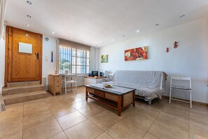 A spacious living area with a sofa, coffee table, and a desk with a computer.