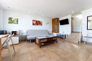 A spacious living area with a sofa, a coffee table, a TV, and a staircase.