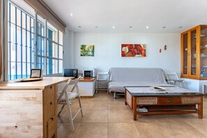 A room with a desk, a bed, a chair, a cabinet, and artwork on the walls.