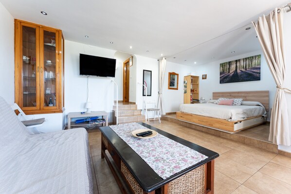 A bedroom with a bed, a TV, a desk, and a mirror.