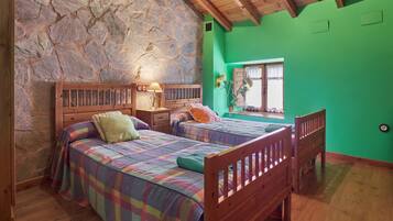 Una habitación con dos camas de madera, una pared de piedra, una pared verde y un techo de madera.