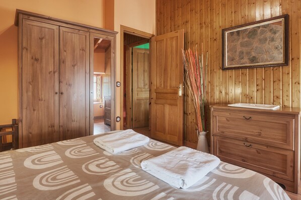 A room with a bed, a wooden wardrobe, a dresser, and a framed picture on the wall.