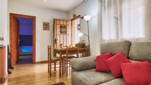 A living room with a sofa, red cushions, a wooden dining table with chairs, a lamp, and a view of a pool through an open door. - Country Home 'Aguas Frias 2' with Mountain View, Private Terrace and Wi-Fi (La Omañuela)