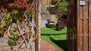 A patio area with a stone wall, a wooden fence, and a green artificial lawn.