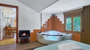 A bedroom with a large bed, a fireplace, a jacuzzi, and a window with a view. - Country Home 'Aguas Frías I' with Mountain View, Private Terrace and Wi-Fi (La Omañuela)