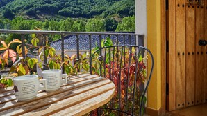 A balcony with a table, two mugs, and a view of a forested hillside. - Country Home 'Aguas Frías I' with Mountain View, Private Terrace and Wi-Fi (La Omañuela)