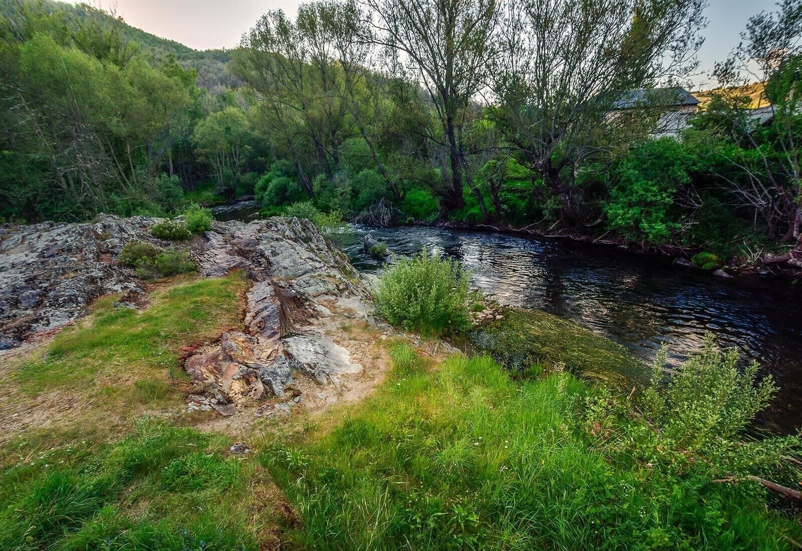 A natural landscape with a river, rocky terrain, and dense greenery.