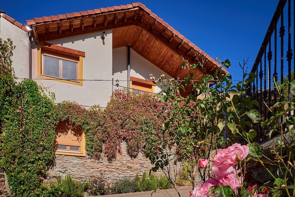 A house with a stone foundation, wooden balcony, and a window with a yellow frame.